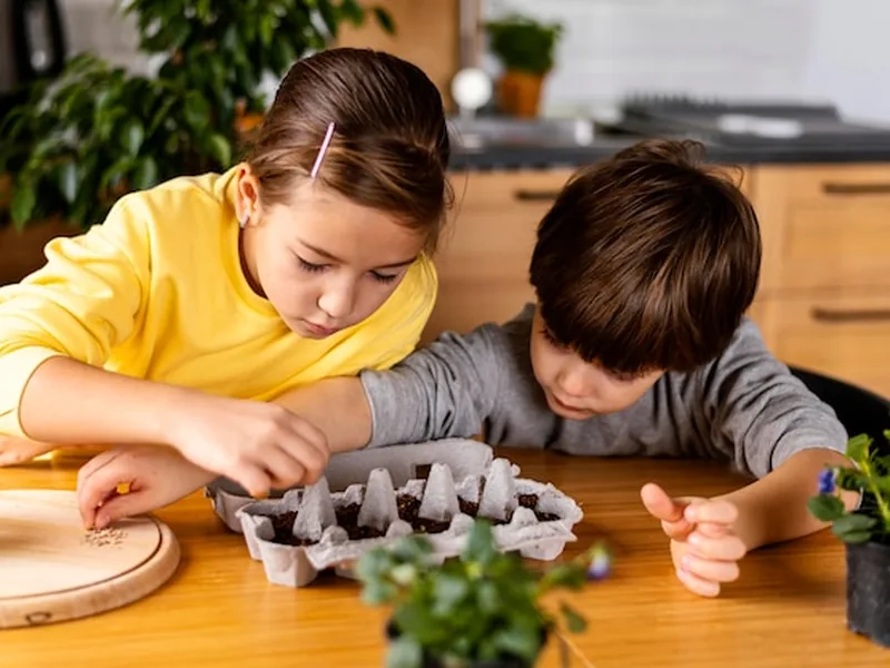 Two children planting seeds together at a kitchen table