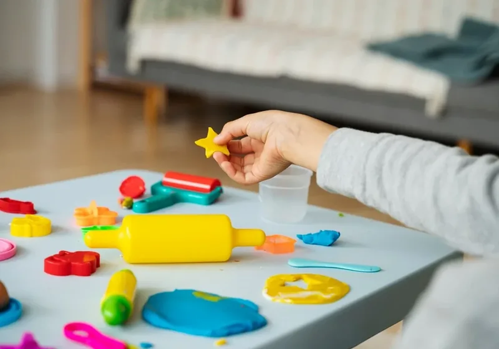 A child pinching a small star-shaped cutter over a table of play dough